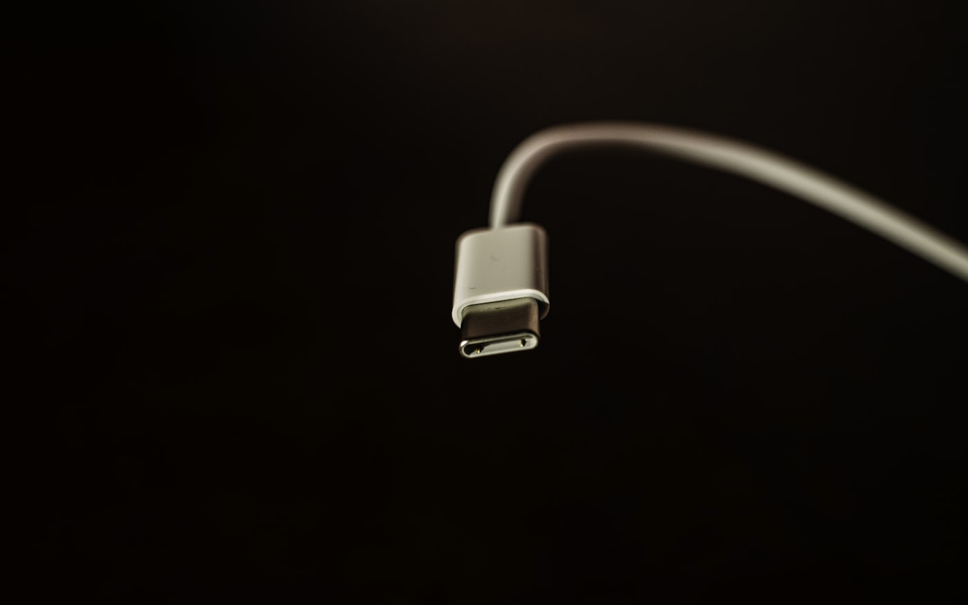 A USB-C connector on a black surface, its contacts catching a single light.