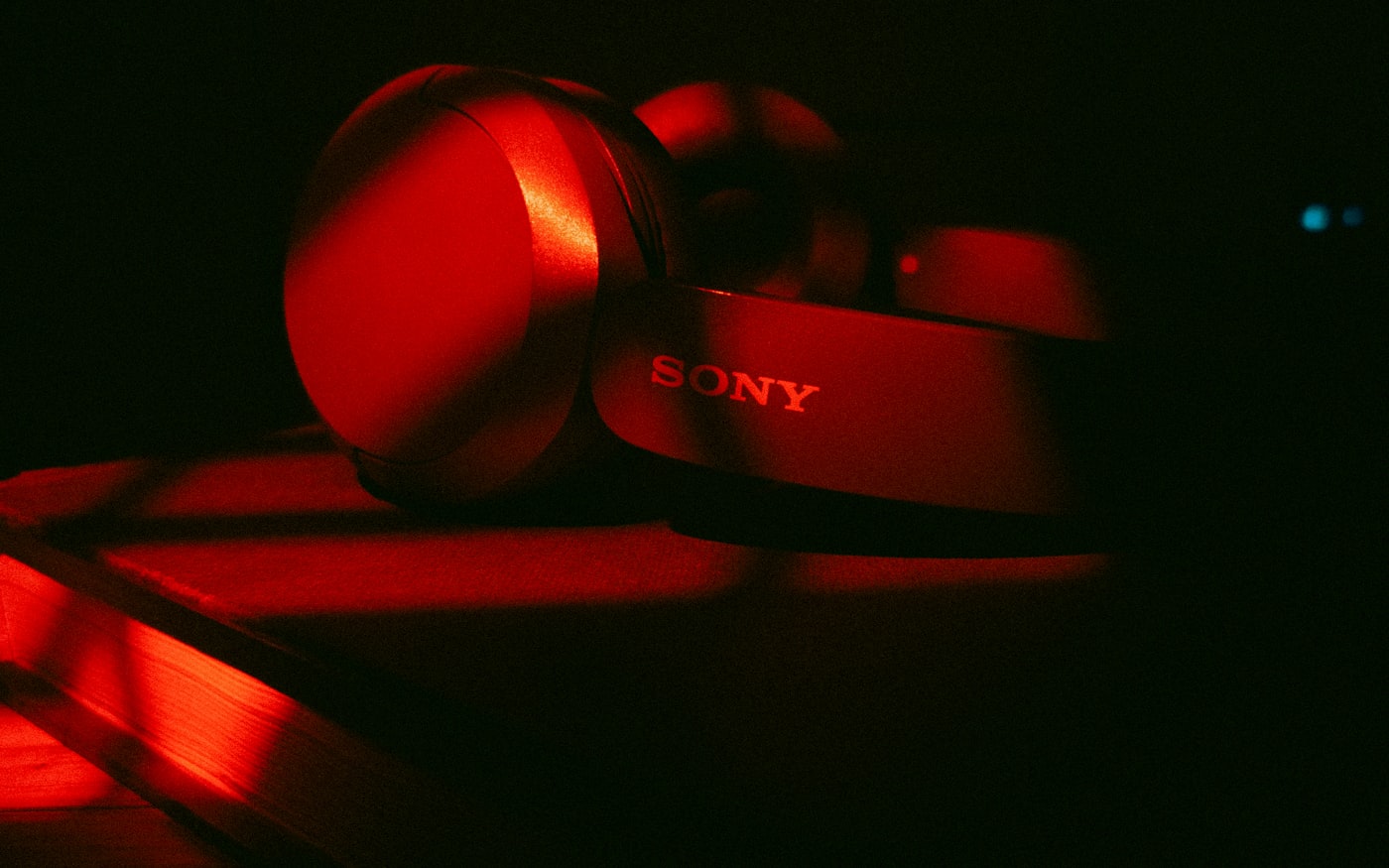 Over-ear headphones lit red in near-darkness.