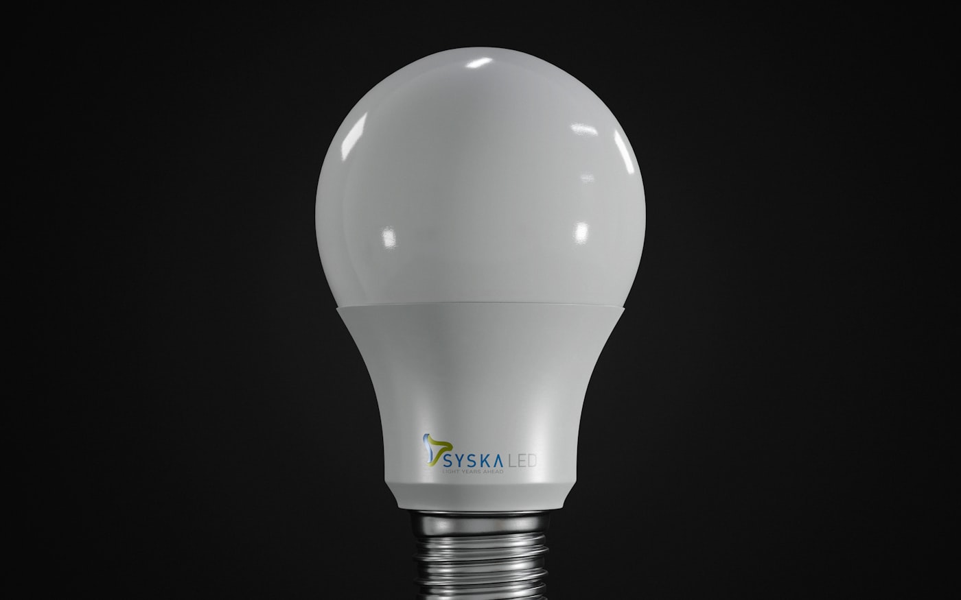 A smart bulb standing on a near-black surface under one soft light.