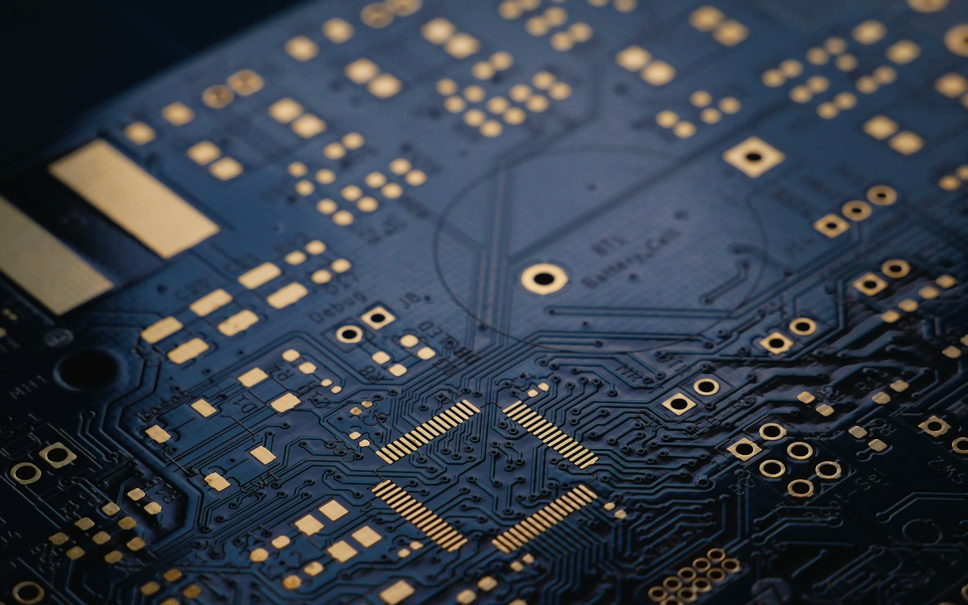 Raking light across the copper traces and solder pads of a bare circuit board.